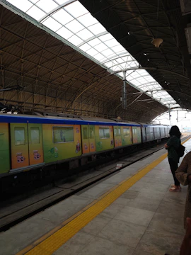 A Mumbai local train covered with vibrant advertising wraps moving through a crowded station.