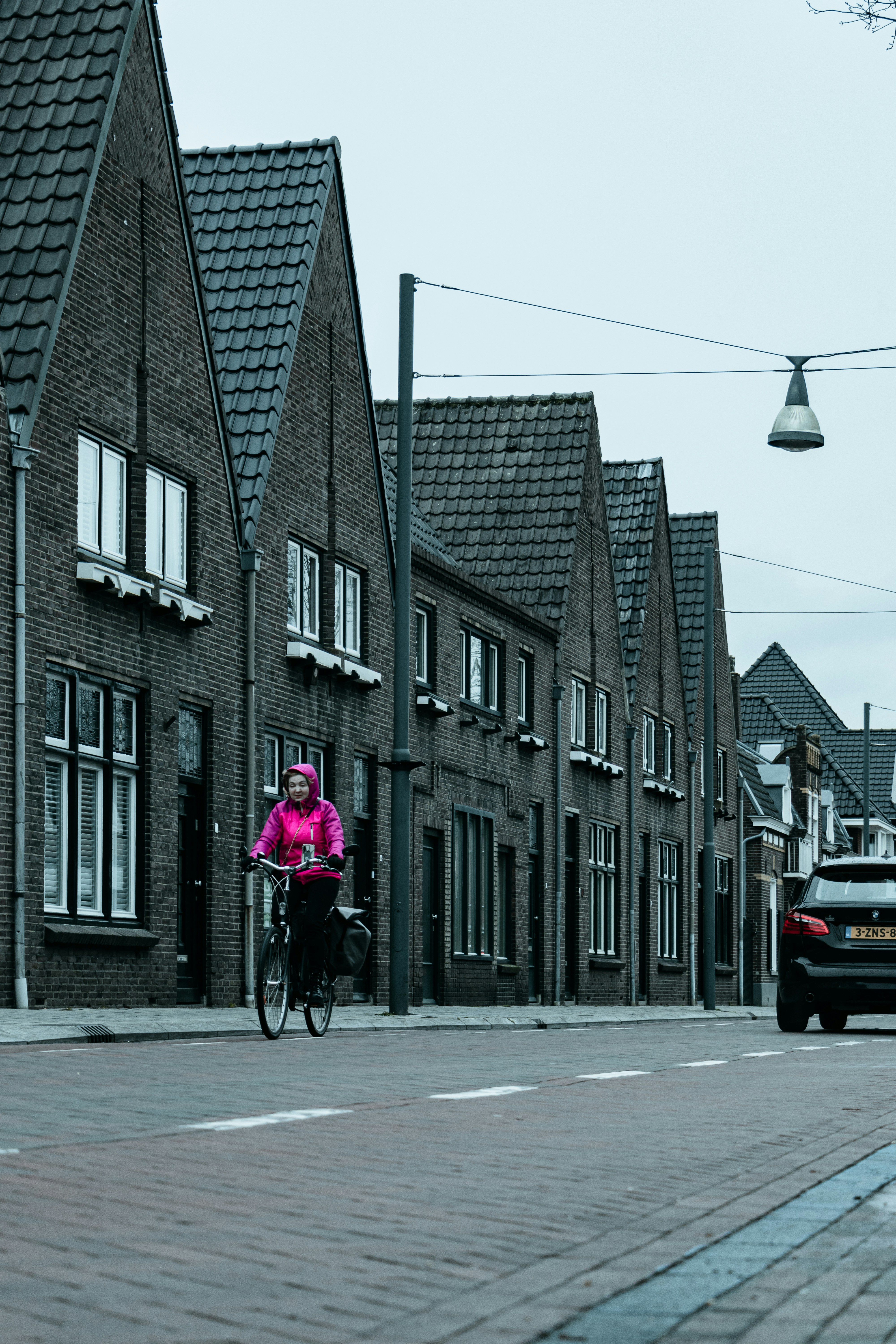 Woman in pink jacket cycling over street in Best, Eindhoven, Netherlands
