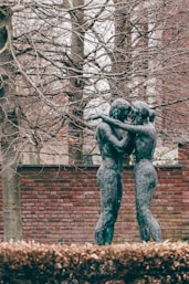 a statue of two people hugging in front of a brick wall