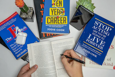 a person holding a pen and writing on a book
