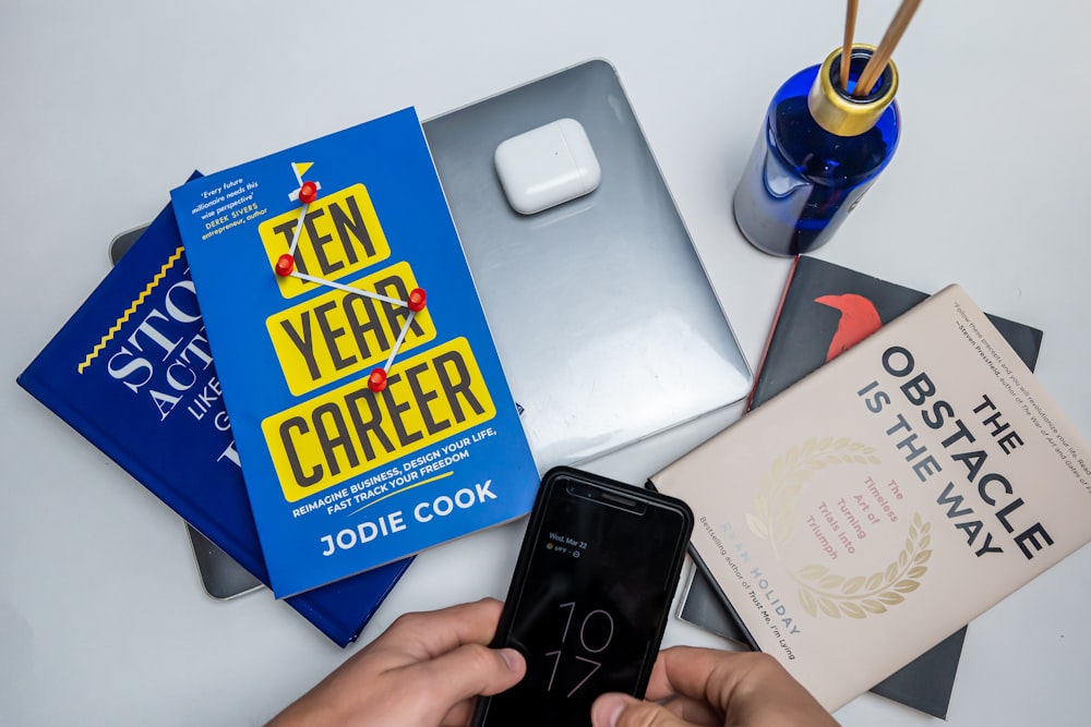 a person holding a cell phone next to a book