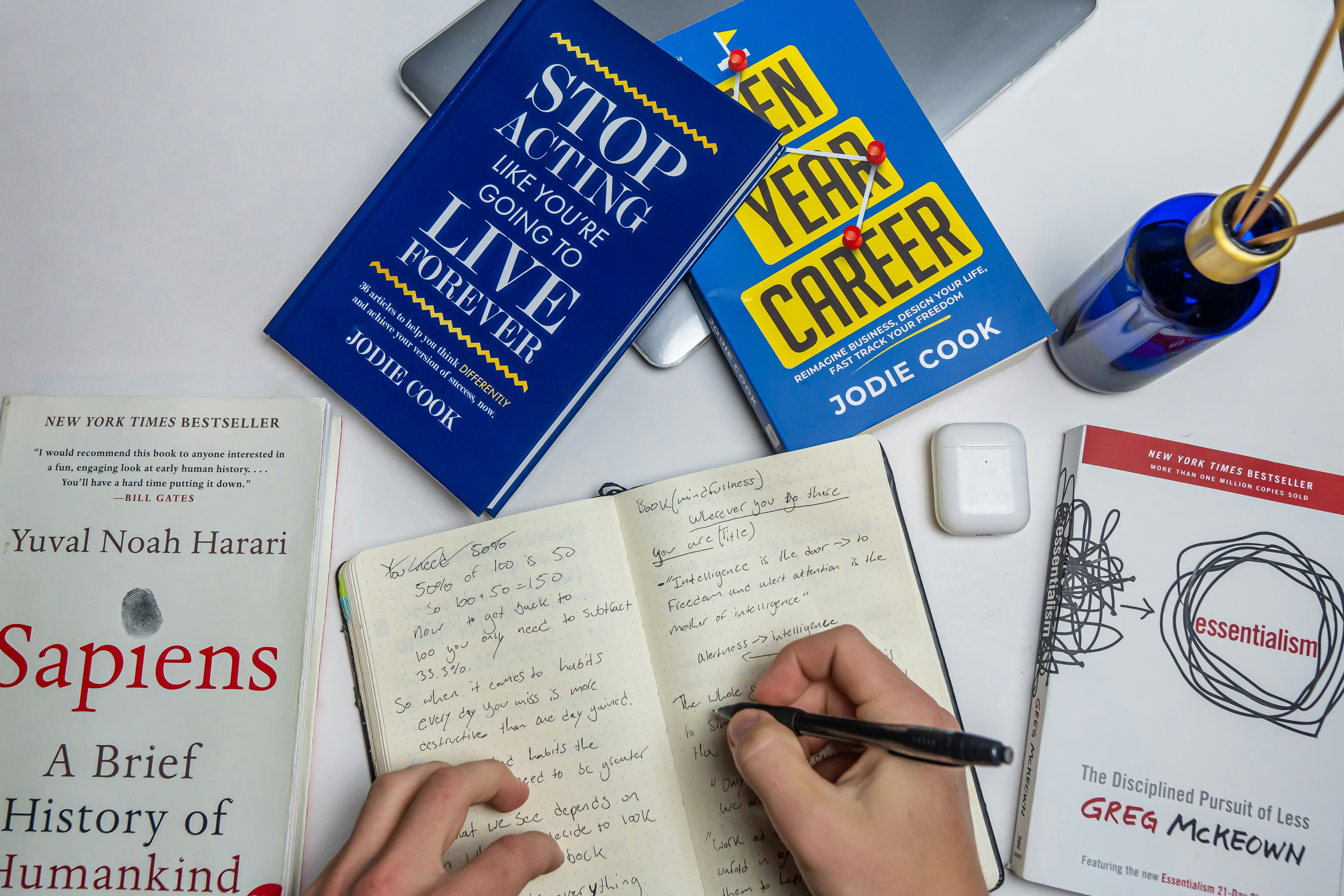 a person writing in a notebook next to some books