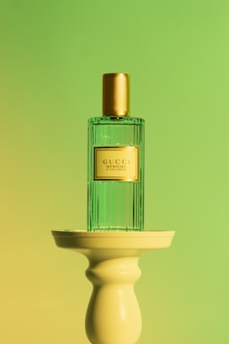 Elegant dark green and gold perfume bottle with soft beige background highlighting luxury scent.