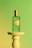 Close-up of a deep emerald green perfume bottle with metallic gold accents on a cream background.