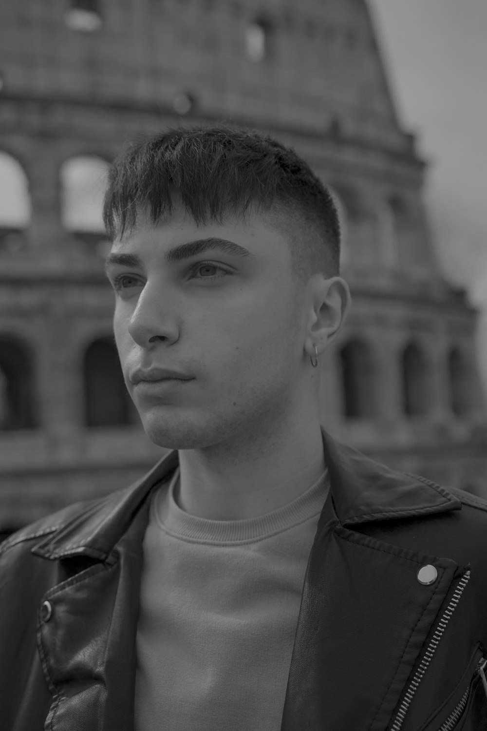 a man in a leather jacket standing in front of a building