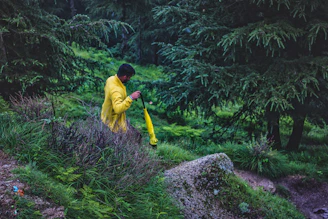 A woman wearing a vibrant Aquashield jacket walking through a misty forest trail.