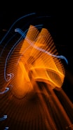 A dynamic abstract pattern of swirling orange and blue light trails against a dark background, creating a sense of motion and energy.