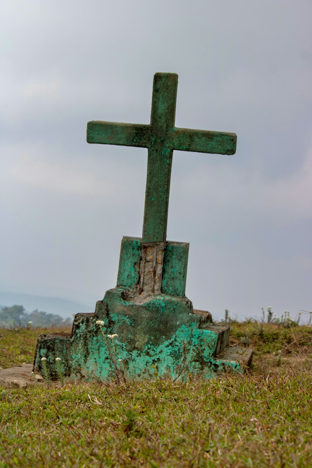 a large green cross sitting on top of a lush green field