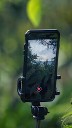 Close-up of a golfer swinging with a smartphone on a tripod capturing the motion outdoors.