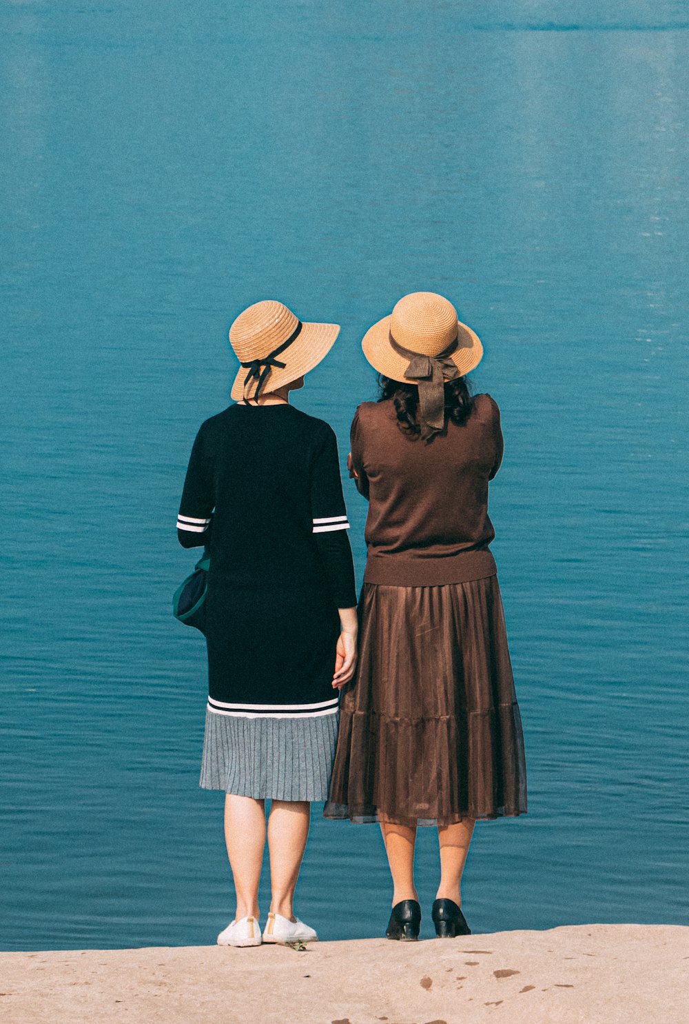 two women standing on the shore of a lake