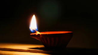 A softly glowing nilavilakku lamp casting warm light over intricate temple carvings.