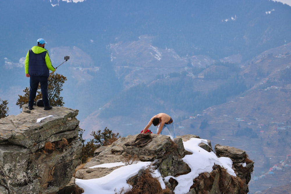 Un uomo in piedi sulla cima di una montagna vicino a rocce coperte di neve