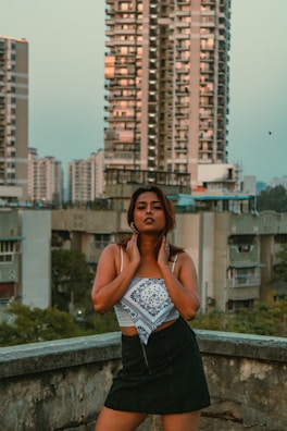 A model wearing vibrant fashion pieces, standing tall on an urban rooftop at sunset.