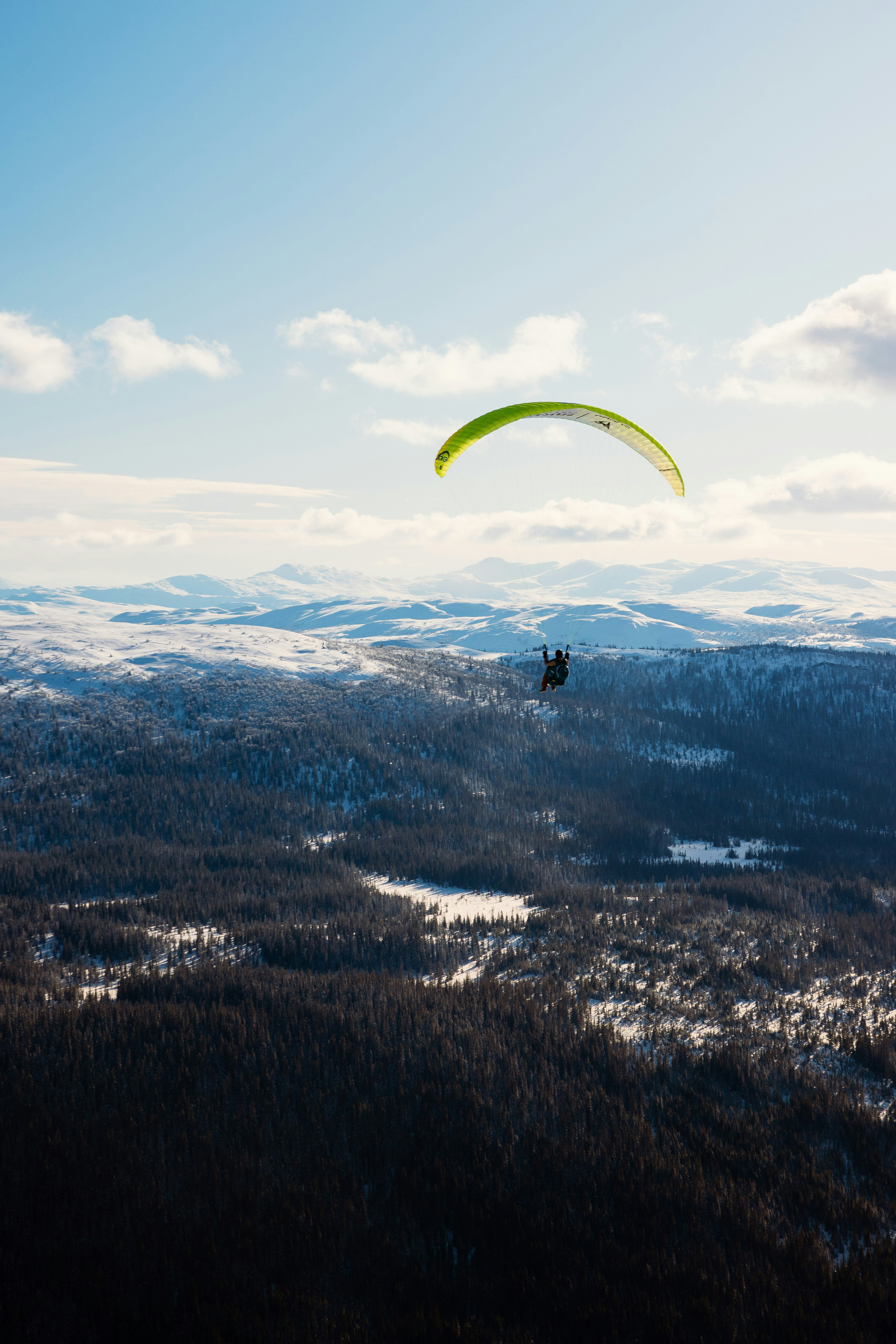 a person is parasailing over a snowy mountain