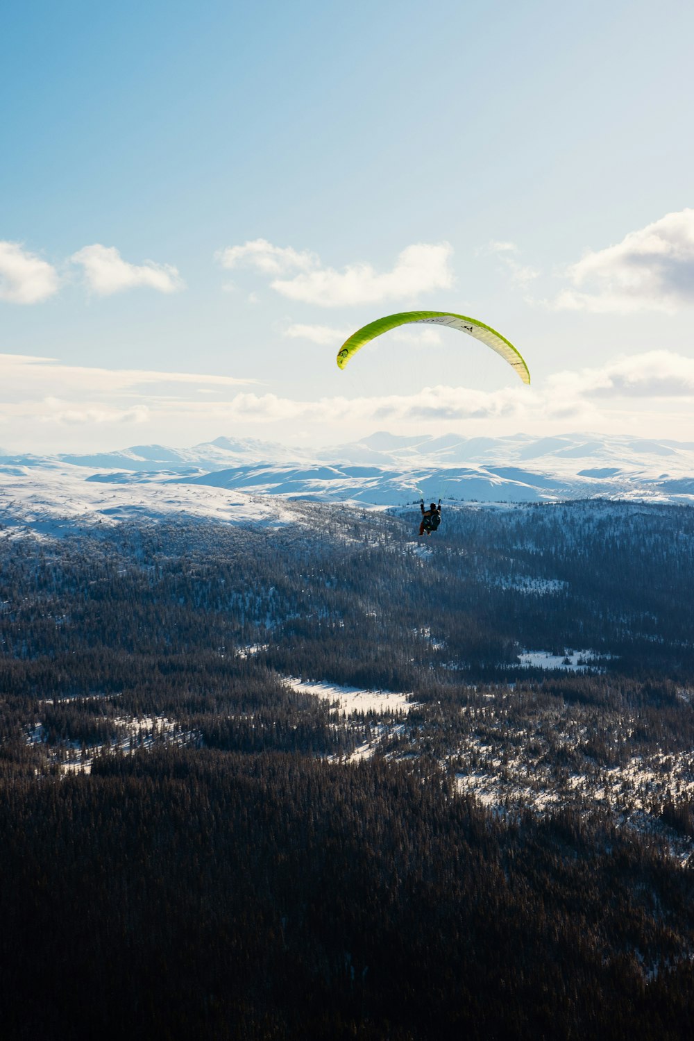 a person is parasailing over a snowy mountain