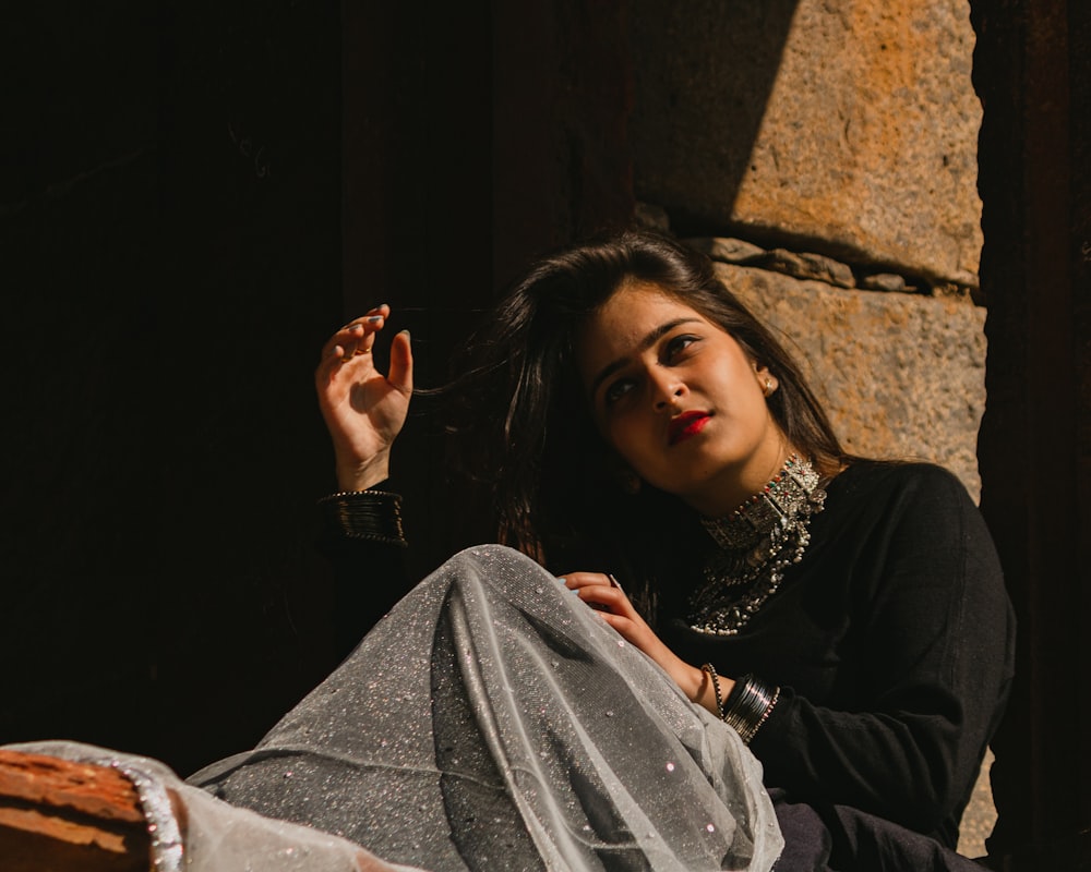 a woman sitting on the ground smoking a cigarette
