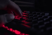 A close-up of hands typing on a keyboard with a ghost icon softly illuminated in the background.