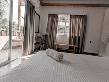 Bright suite featuring a comfortable bed and a small balcony with garden view.
