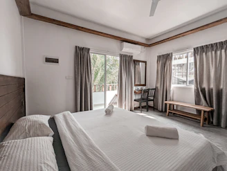 Well-lit bedroom with minimalist decor and large windows.