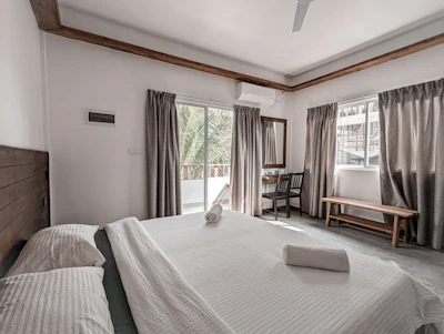 Well-lit bedroom with minimalist decor and large windows.