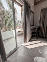 Bright, airy deluxe room with beach-inspired decor and a balcony overlooking palm trees.