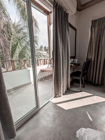 Bright, airy deluxe room with beach-inspired decor and a balcony overlooking palm trees.