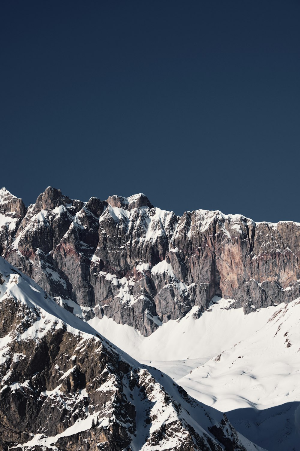 a large mountain covered in snow under a blue sky