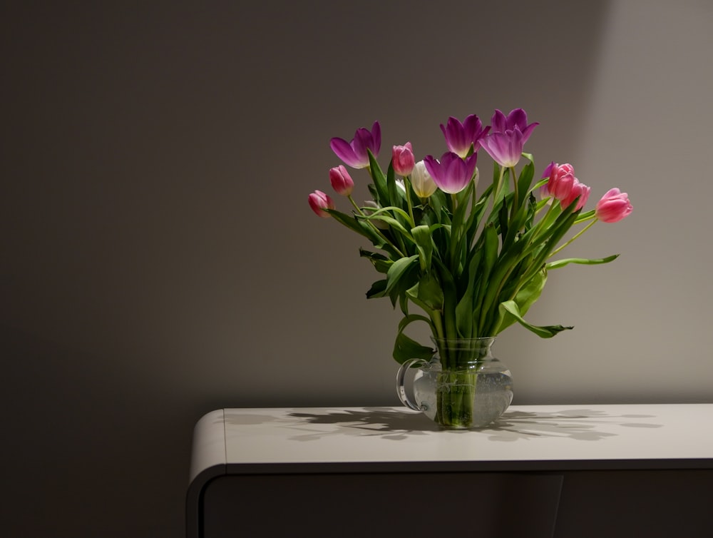 a glass vase filled with pink and purple tulips