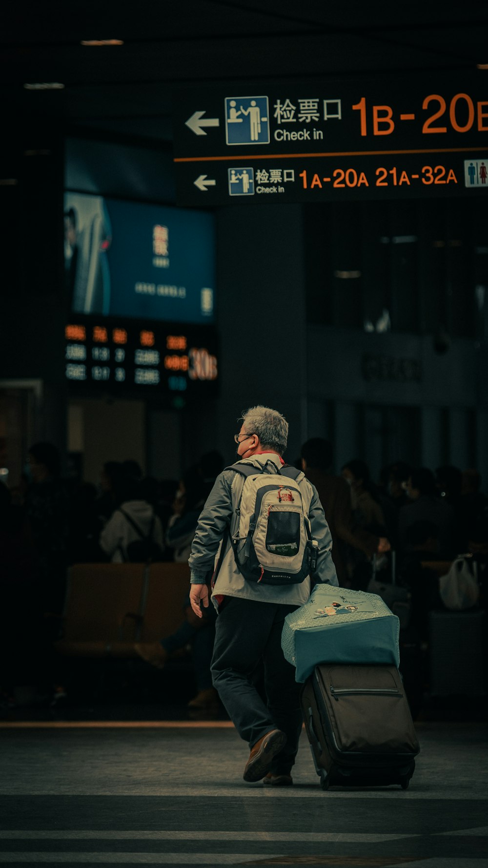 a man with a backpack and suitcase walking through an airport