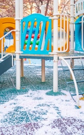 a playground with a blue slide and a yellow slide
