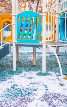 a playground with a blue slide and a yellow slide