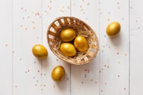 a basket filled with golden eggs on top of a white table