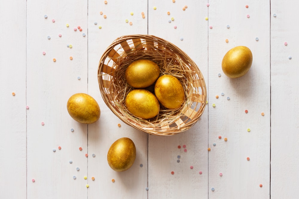a basket filled with golden eggs on top of a white table