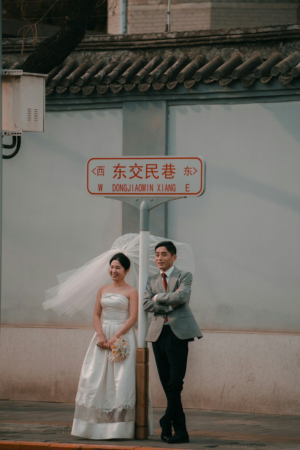 a bride and groom standing under a street sign