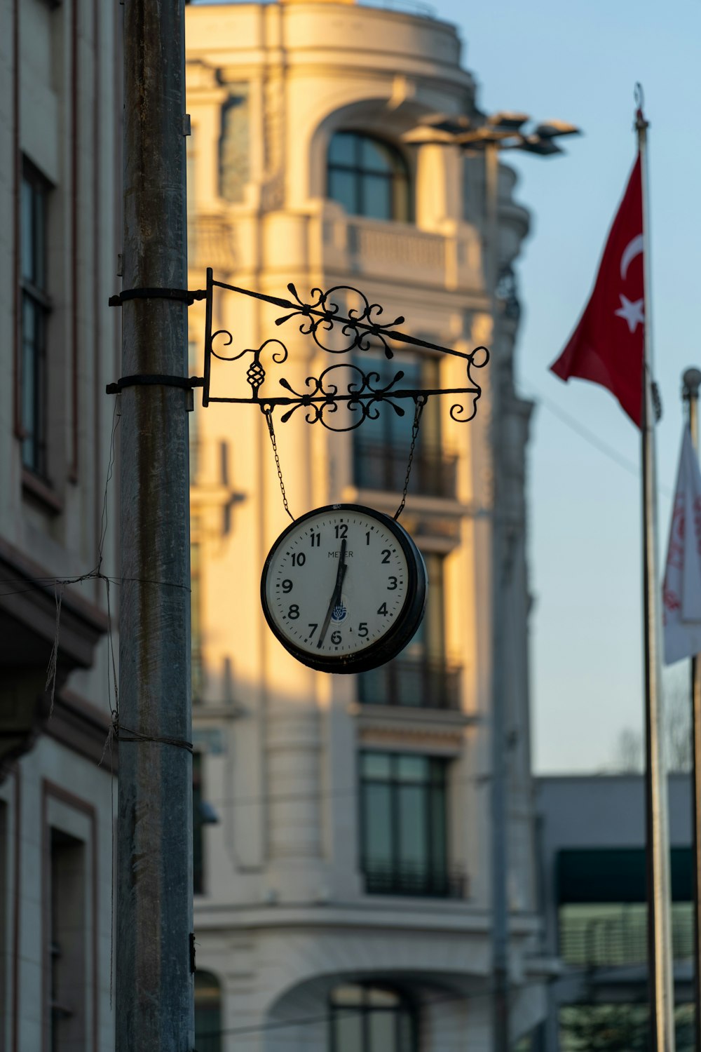 a clock hanging from a pole in front of a building