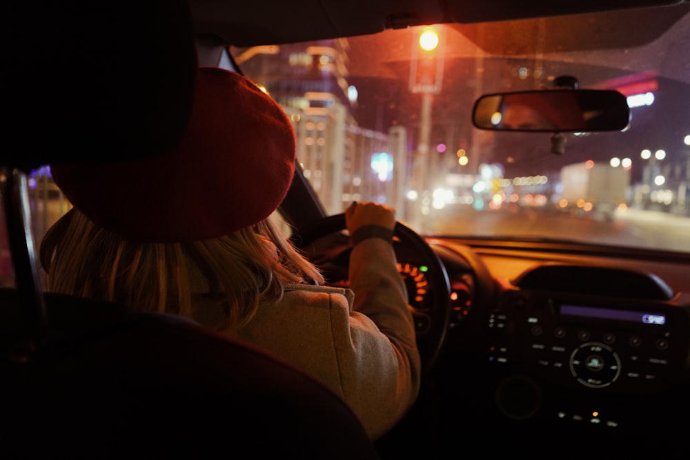 도시 거리에서 밤에 차를 운전하는 여자