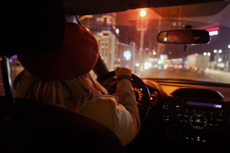 Driving through a city at night past bright headlights and streetlights