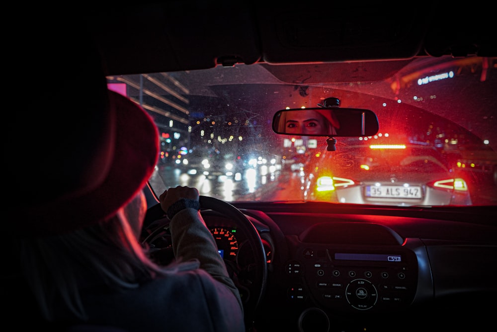 Una mujer conduciendo un coche por la noche bajo la lluvia