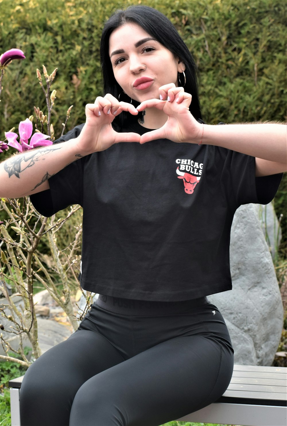 a woman sitting on a bench making a heart with her hands
