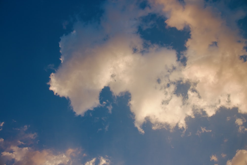 a plane flying through a cloudy blue sky