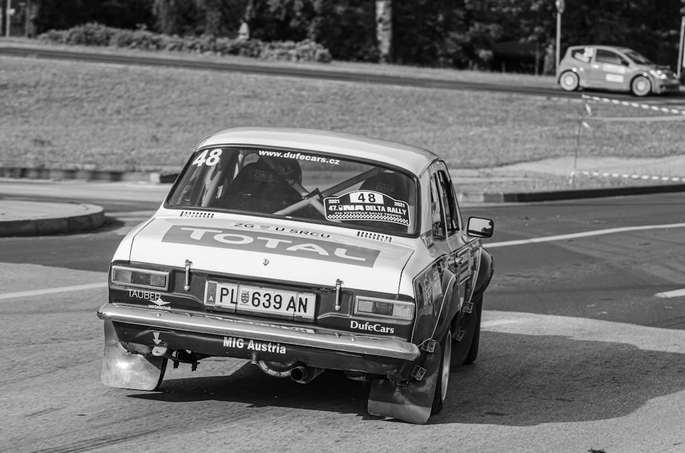 a black and white photo of a car on a race track