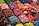 An assortment of colorful candy displayed in clear containers, featuring a variety of shapes and textures. The selection includes sweets that resemble berries, citrus slices, and marshmallows, arranged in an eye-catching, organized layout.