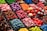 An assortment of colorful candy displayed in clear containers, featuring a variety of shapes and textures. The selection includes sweets that resemble berries, citrus slices, and marshmallows, arranged in an eye-catching, organized layout.