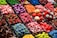 An assortment of colorful candy displayed in clear containers, featuring a variety of shapes and textures. The selection includes sweets that resemble berries, citrus slices, and marshmallows, arranged in an eye-catching, organized layout.