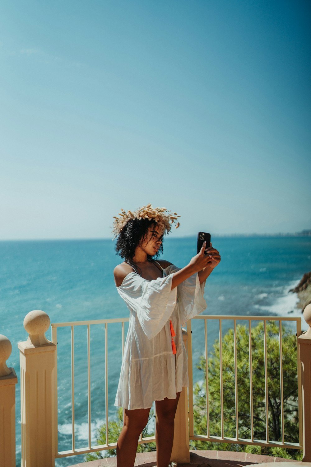 a woman taking a picture of the ocean with her cell phone