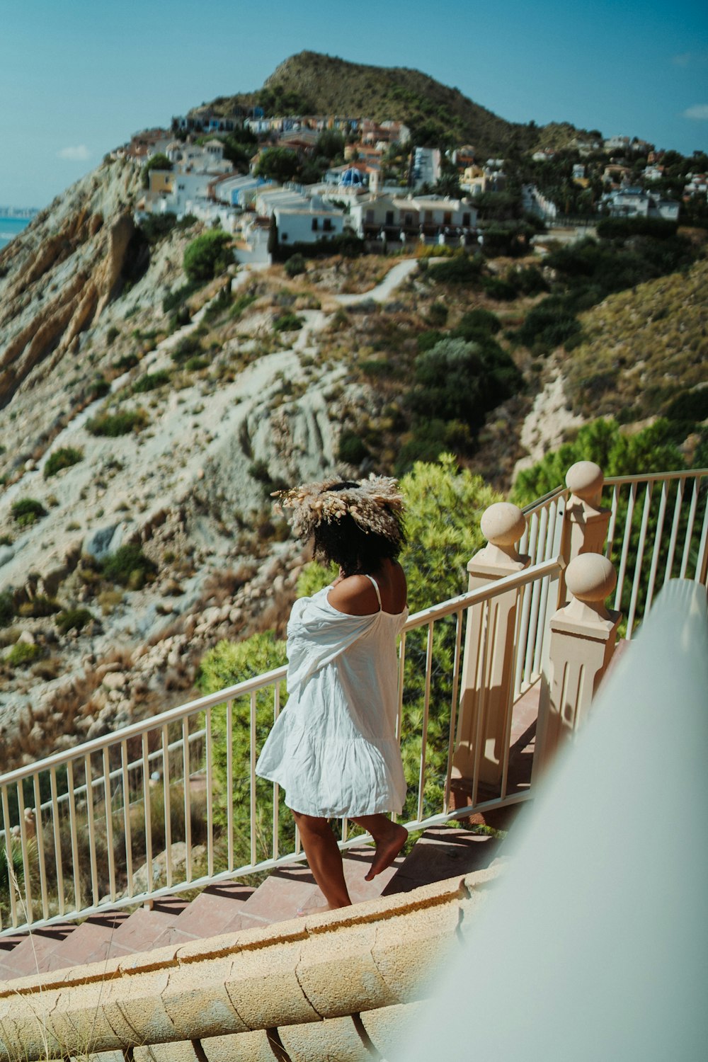 a woman in a white dress standing on a balcony