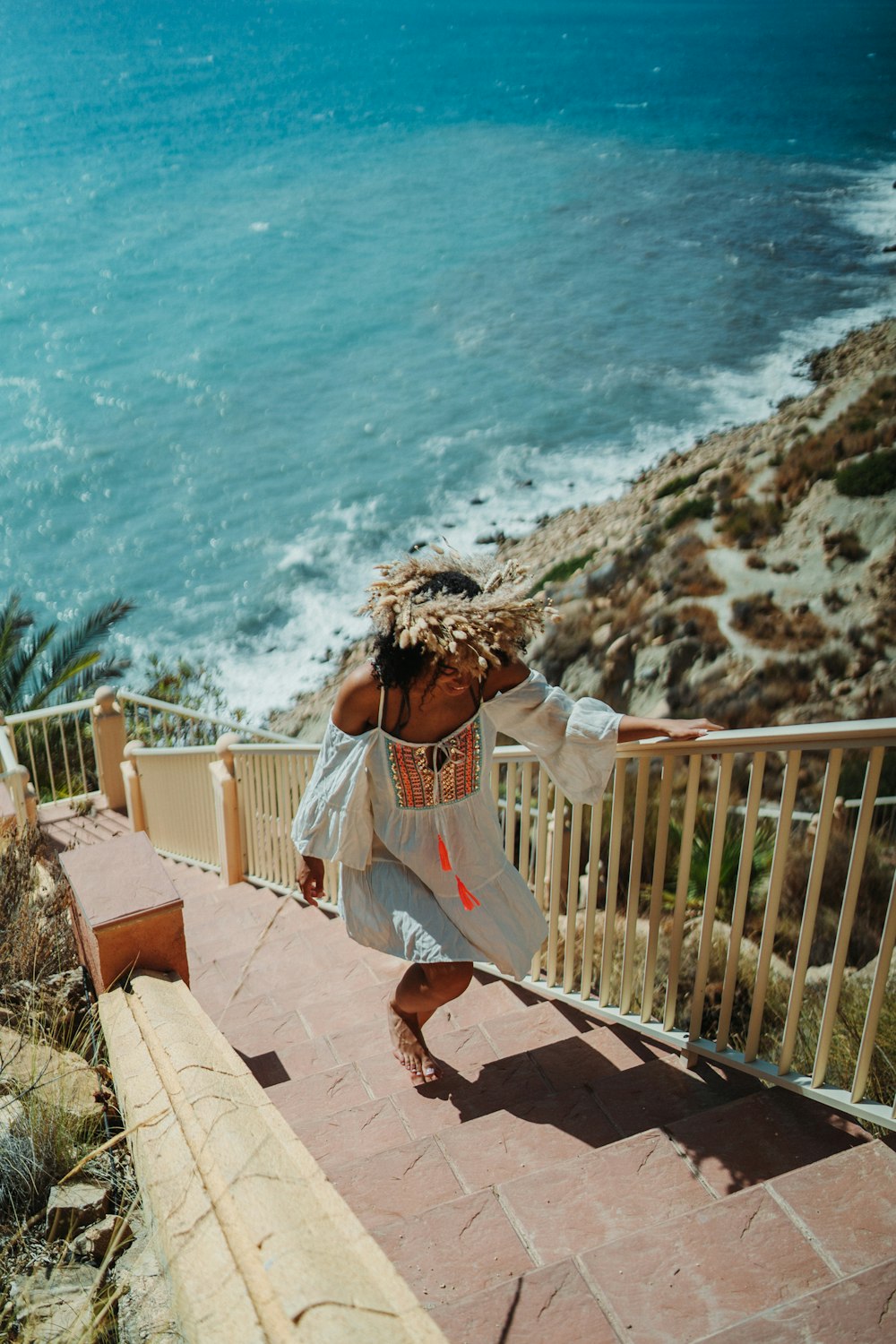 a woman in a white dress is walking down a set of stairs