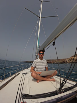 An adventurous sailor checking weather updates on a digital device while preparing to set sail.