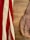 A vintage leather bag lies on a wooden surface, next to a fabric with red and white stripes.