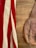 A vintage leather bag lies on a wooden surface, next to a fabric with red and white stripes.